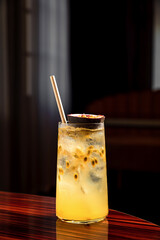 A refreshing long drink with passion fruit in a highball cocktail glass filled with ice cubes