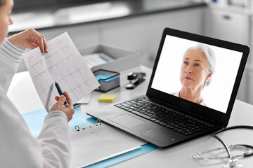 healthcare, technology and medicine concept - female doctor in white coat with laptop computer and...