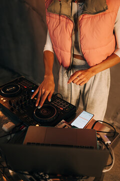 Close photo of female DJ hands playing music on remote control with laptop indoors. The work of a DJ.