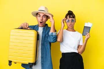 Young traveler friends holding a suitcase and passport isolated on yellow background has just realized something and has intending the solution