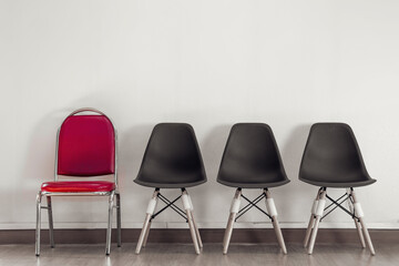 Selected red chairs in rows of chairs on wooden floor against white wall background. Vintage style. concept for business in job interview. Selection and job vacancies. with copy space