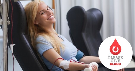 Portrait of smiling young woman donating blood sitting on chair by symbol at hospital