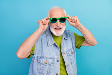 Photo of cool pretty retired man wear vintage jeans waistcoat arms dark glasses smiling isolated blue color background
