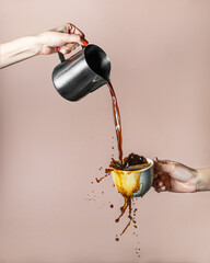 Coffee is poured into a cup with splashes on a beige background