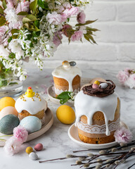 Easter cakes decorated with white glaze with Easter eggs and flowers on a light background