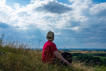 Naklejka na ściany i meble Young man admiring beautiful view of the forest landscape rear view.Young man standing alone summer day outdoors.