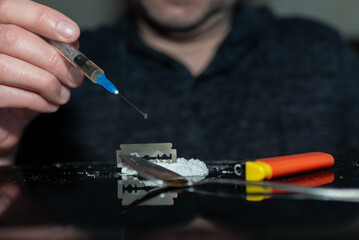 Syringe taking in the heroin.addict dark room.drug addict man preparing for the next dose.Toned.Selective focus.