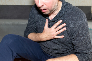 Unshaved Anxious man at home feeling chest pain, overworked manager, heart attack.Side...
