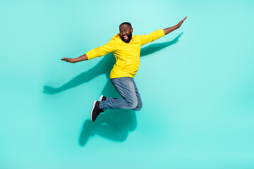 Obraz premium Full size photo of excited guy jumping hands flying bird isolated over cyan color background