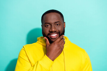 Photo of brunette cool young beard guy touch beard wear yellow sweatshirt isolated on teal color background