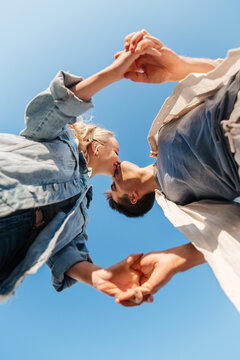 Summer Holidays, Love And People Concept - Happy Young Couple Kissing Under Blue Sky, From Below