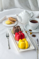 dessert Mousse Cakes covered with colorful velvet spray and cup of tea on the table