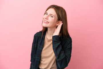 Fototapeta na wymiar Young English woman isolated on pink background listening to something by putting hand on the ear