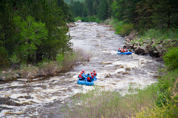 USA, Colorado. The Cache la Poudre river cascades while rafters ride through whitewater in northern...