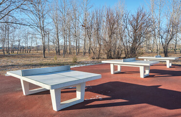 Table tennis tables in autumn public park.