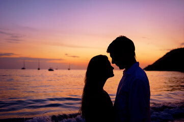 Fototapeta premium Silhouette of a couple in love on a sunset tropical background.