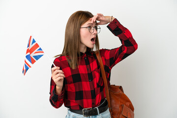 Young woman holding an United Kingdom flag isolated on blue background doing surprise gesture while looking to the side