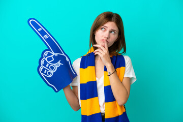Young sports fan woman isolated on blue background having doubts while looking up