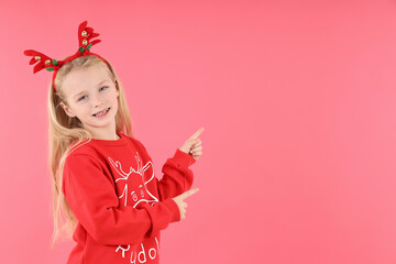 Little girl in Christmas clothes on pink background
