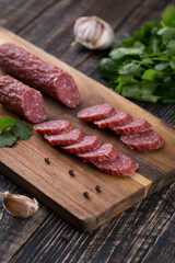 Fresh sausages and ham slices on wooden cutting board, delicious snack, spicy and high quality meat products made of pork and veal, beef.