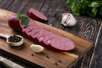 Fresh sausages and ham slices on wooden cutting board, delicious snack, spicy and high quality meat...