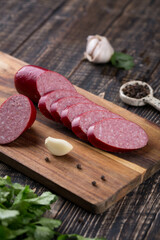 Fresh sausages and ham slices on wooden cutting board, delicious snack, spicy and high quality meat products made of pork and veal, beef.