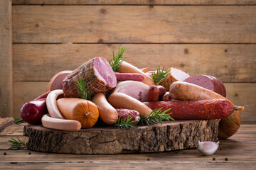 Variety of delicious fresh sausages and hams on wooden cutting board, delicious snack, spicy and...