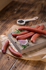 Fresh sausages and ham slices on wooden cutting board, delicious snack, spicy and high quality meat...