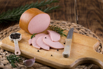 Fresh sausages and ham slices on wooden cutting board, delicious snack, spicy and high quality meat...