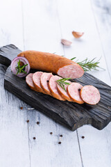 Fresh sausages and ham slices on wooden cutting board, delicious snack, spicy and high quality meat...