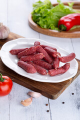 Fresh sausages and ham slices on wooden cutting board, delicious snack, spicy and high quality meat products made of pork and veal, beef.