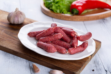 Fresh sausages and ham slices on wooden cutting board, delicious snack, spicy and high quality meat products made of pork and veal, beef.