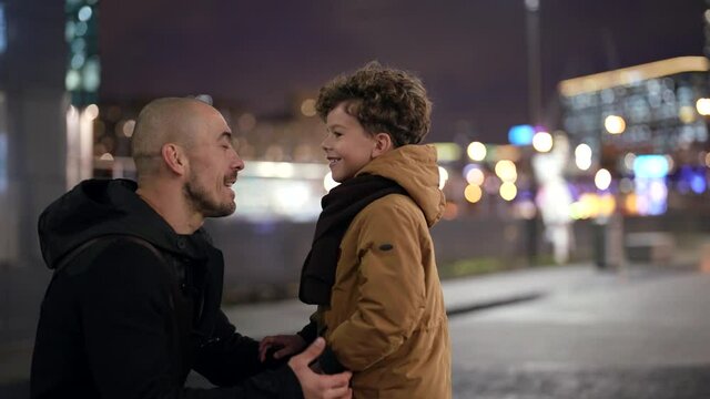 father and little son on city street in evening, adult man is communicating with little boy