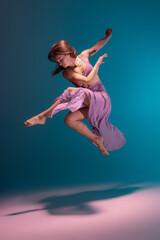 One young flexible contemp dancer in lilac dress dancing isolated on gradient blue white background in neon.