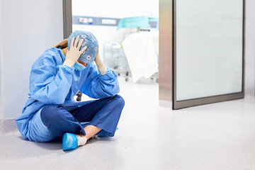 Exhausted doctor or nurse sits in front of the operating room