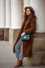Elegant fashionable woman wearing trendy midi brown faux fur teddy bear coat, hat, checked...