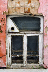 Wooden window with a hole for a samovar pipe, in the wall of the basement of an old house. The...
