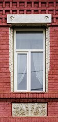 A modern plastic double-glazed window in the window of an old brick building with elements of stucco decoration. The picture was taken in Russia, in the city of Orenburg