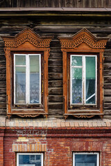 Windows with carved wooden frames, a fragment of the facade of an old building. The picture was taken in Russia, in the city of Orenburg