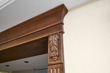 Decorated wooden doorway with carved furniture brackets and fluted panel in classic style in light...