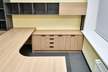 Work desk with storage cabinet with drawers with wall mounted shelves made of laminated chipboard with wood and stone texture pattern in office