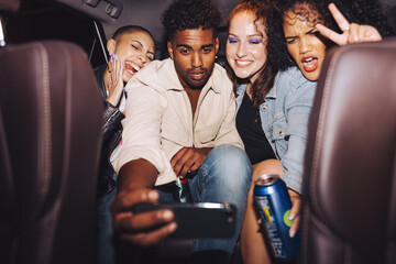 Diverse group of friends taking a selfie in a car