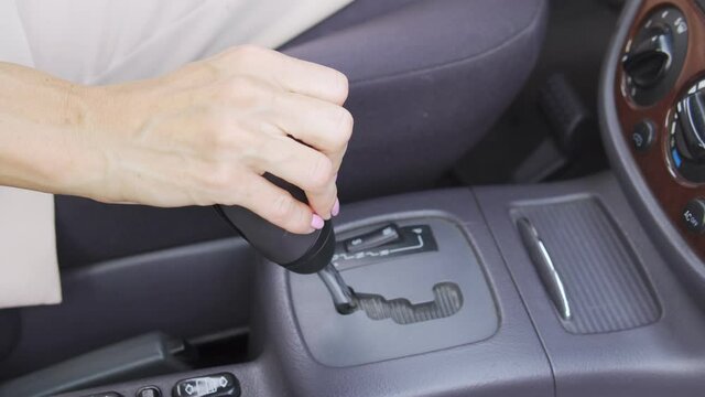 Close up woman hand changing gears, driving car with automatic transmission