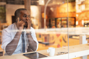 Businessman drinking coffee in cafe. Handsome African man talking to the phone while enjoying in fresh coffee..