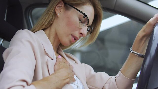 Unhappy female having panic attack in car, suffering chest pain, health problem