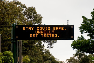 Changeable electronic dynamic road sign reads: 'Stay COVID safe. Unwell. Get tested' on the city...
