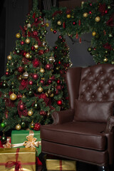 A decorated Christmas tree on the background of leather chair at home: a place for text, a home Christmas interior, vertical image