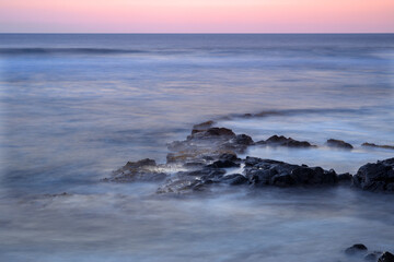 USA, Hawaii, Big Island of Hawaii. Kohanaiki Beach Park, Dawn sky over waves and volcanic rock.