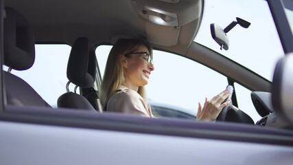 Pleased young woman sitting in new car dancing and smiling, celebrating purchase