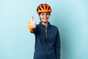 Young cyclist woman isolated on blue background with thumbs up because something good has happened